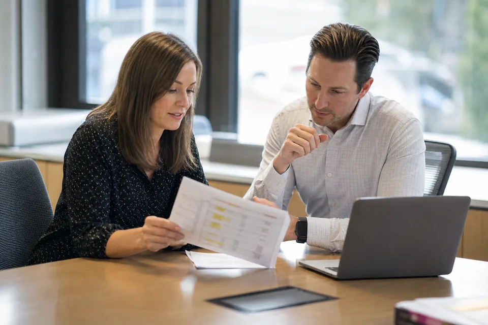 Procurement manager and controller reviewing a multi-year EHS software subscription quote at a conference table