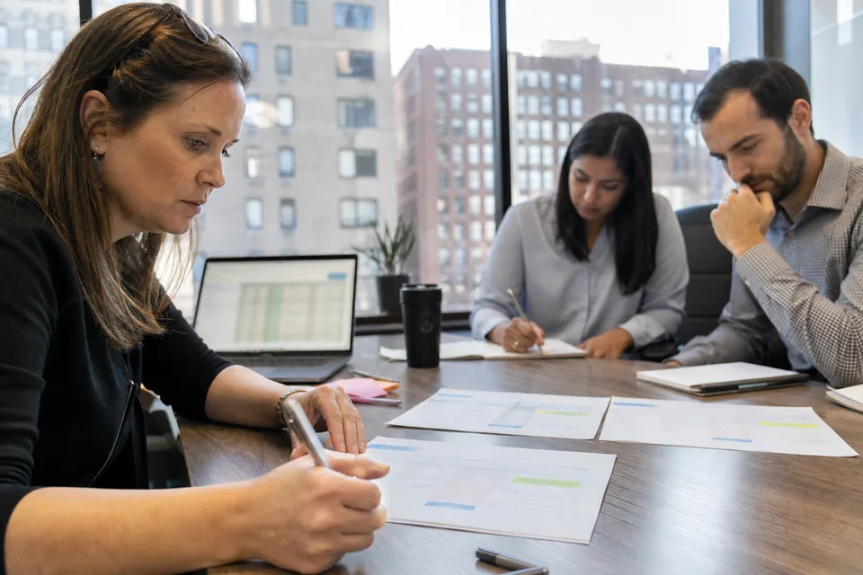 Procurement manager comparing printed vendor proposals for carbon accounting software at a meeting table