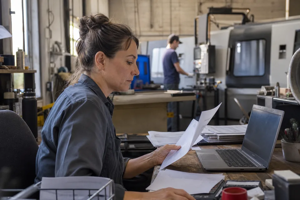 Owner of a small US manufacturing business reading a customer's supplier emissions questionnaire at a workshop desk
